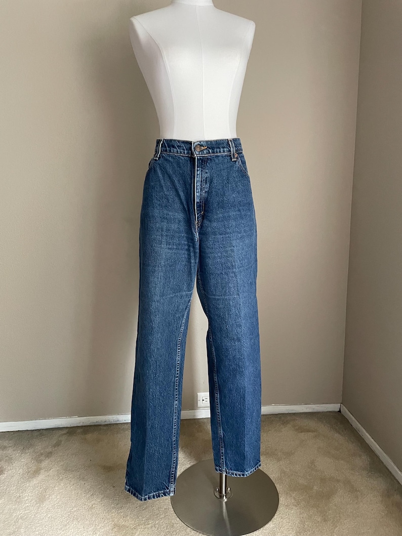 Peut inclure: Un jean bleu denim &agrave; taille haute et &agrave; jambe droite. Le jean est sur un mannequin.