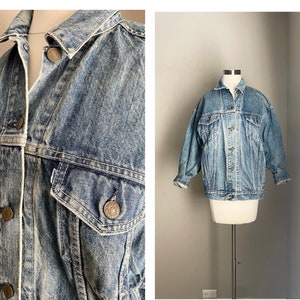 May include: A light blue denim jacket with a classic design. The jacket has a button-up front, two chest pockets, and two front pockets. The jacket is distressed and faded, giving it a vintage look.