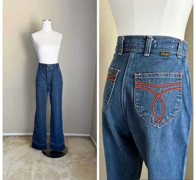 K&ouml;nnte beinhalten: Blaue Wrangler Jeans aus Denim mit hoher Taille und ausgestellten Beinen. Die Ges&auml;&szlig;taschen haben ein orangefarbenes Nahtdesign. Die Jeans werden auf einer Schaufeniquin pr&auml;sentiert.