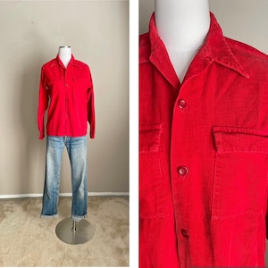May include: A red corduroy shirt with a button-down collar and two chest pockets. The shirt has a long sleeve and is made of a soft, comfortable fabric.
