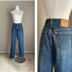 Peut inclure: Un jean bleu denim avec un &eacute;cusson en cuir brun sur la poche arri&egrave;re qui dit "Levi's" en lettres blanches. Le jean a une jambe droite et une taille haute.