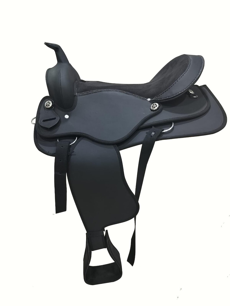 May include: A black Western saddle with a high cantle and horn. The saddle features a suede seat and leather skirts, stirrups, and fenders. Silver-colored conchos and D-rings are visible. The saddle is designed for horseback riding.