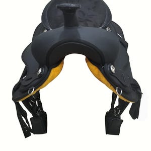 May include: A black Western saddle with a textured seat and yellow padding. The saddle features silver-toned hardware and adjustable straps. The design is suitable for equestrian activities and horse riding.