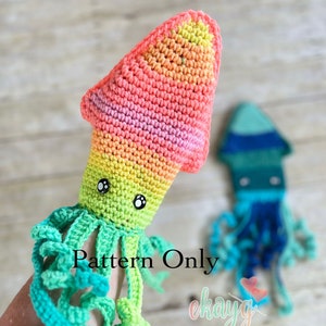 Könnte beinhalten: Ein gehäkelter Regenbogen-Tintenfisch mit grünen Tentakeln und schwarzen Augen. Der Tintenfisch wird in der Hand einer Person gehalten. Der Text "Pattern Only" ist im Bild sichtbar.
