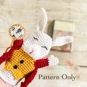 May include: Crochet pattern for a white rabbit puppet with a red and yellow vest and a pocket watch. The pattern is for a hand puppet and includes instructions for making the rabbit, vest, and pocket watch.