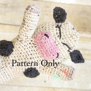 May include: Crochet cow mitten pattern. The mitten is beige with black and pink details. The pattern is for sale.