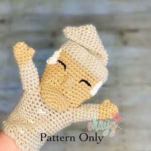 May include: Crochet pattern for a gnome puppet with a beige hat and a beige and brown body. The gnome has a smiling face with closed eyes and a small white nose. The text "Pattern Only" is visible in the image.