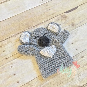 May include: A gray crocheted koala puppet with white ears and a white belly. The puppet has a black nose and black eyes.