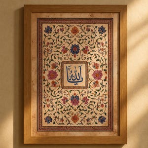 May include: A rectangular framed wall art piece featuring a central blue Arabic calligraphy inscription surrounded by an intricate, symmetrical floral pattern in shades of pink, orange, blue, and green on a parchment-colored background.