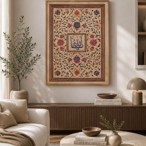May include: A rectangular framed wall art piece featuring a central blue Arabic calligraphy script surrounded by an intricate, symmetrical floral pattern in shades of pink, orange, and blue on a cream background, enclosed in a light wood frame.