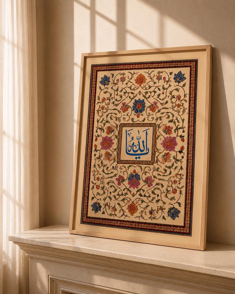 May include: A framed rectangular artwork featuring a central blue Arabic calligraphy inscription surrounded by an intricate floral pattern with pink, orange, and blue blossoms on a cream background, enclosed in a thin light-colored wooden frame.