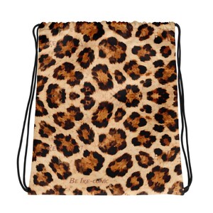 May include: Drawstring bag with a leopard print pattern in shades of brown and black. The bag has black drawstrings and the text "BE IKE-CONIC" at the bottom.