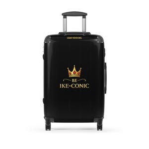 May include: Black rolling suitcase with a retractable handle. The suitcase features a gold crown design with the words "BE IKE-CONIC" and "LEGACY NEVER DIES" in gold lettering. The suitcase has four wheels and a black handle.
