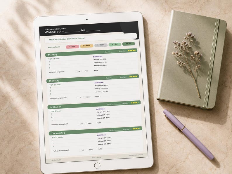 May include: A white tablet displaying a weekly planner with green and pink accents, a sage green notebook with a sprig of dried flowers, and a lavender pen. The planner is open to a page with German text.
