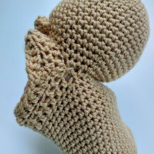 Pu&ograve; includere: Un cappello e guanti abbinati di colore beige in crochet. Il cappello ha una corona arrotondata e i guanti hanno un design semplice.