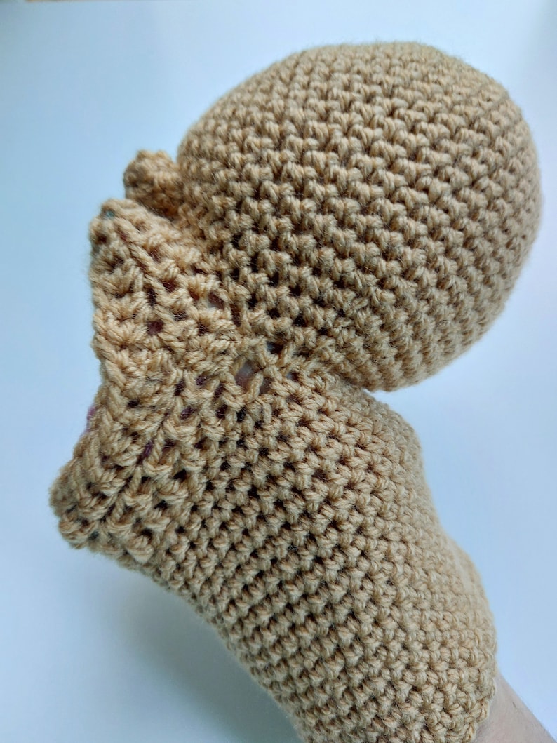 Pu&ograve; includere: Un cappello e guanti abbinati di colore beige in crochet. Il cappello ha una corona arrotondata e i guanti hanno un design semplice.