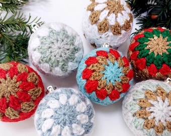May include: A collection of handmade crochet Christmas ornaments in various colors. The ornaments feature intricate floral patterns in white, red, gold, green, and blue. Each ornament has a silver cap for hanging and is displayed on a white surface with greenery.