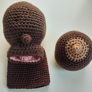 Pu&ograve; includere: Un cappello a uncinetto marrone con fodera rosa e una forma di seno a uncinetto marrone abbinata.