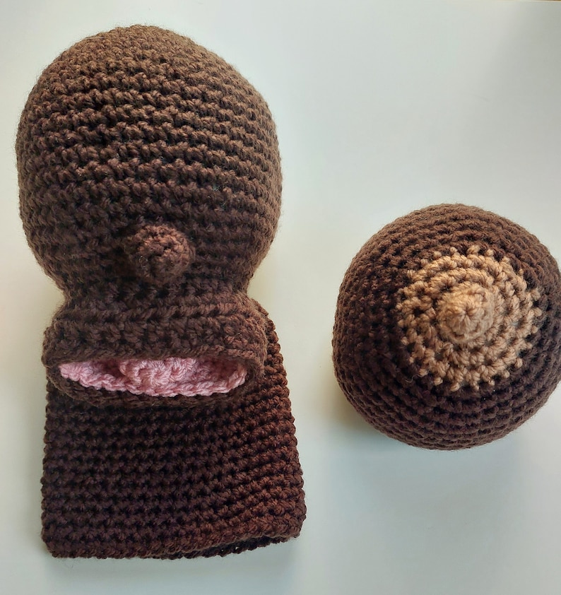 Pu&ograve; includere: Un cappello a uncinetto marrone con fodera rosa e una forma di seno a uncinetto marrone abbinata.