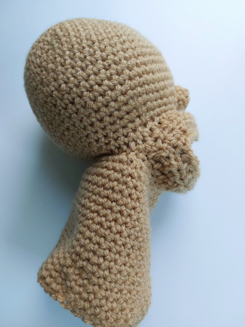 Pu&ograve; includere: Una testa e un corpo di bambola all'uncinetto di colore marrone chiaro. La bambola &egrave; realizzata a uncinetto a punto basso.