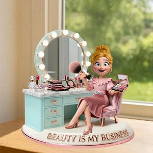 May include: A figurine of a woman seated at a vanity table. The table is light blue with a marble top and a round mirror with lights. The woman holds a makeup brush and palette. The base reads "BEAUTY IS MY BUSINESS."