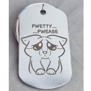 Könnte beinhalten: Silberfarbene Hundemarke mit der Gravur "PWETTY... ...PWEASE" und einer Cartoon-Illustration eines traurigen Hundes. Die Marke hat eine abgerundete rechteckige Form und ein kleines Loch oben.