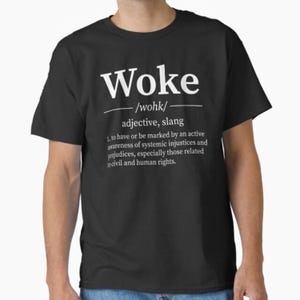 May include: A black short-sleeved t-shirt featuring white text that reads Woke, followed by the phonetic pronunciation /wohk/, the label adjective, slang, and a dictionary-style definition regarding awareness of systemic injustices and prejudices.