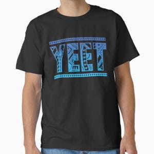 May include: Black t-shirt with the word "YEET" in a blue gradient font. The word is framed by decorative lines and patterns. The shirt is a casual wear item.