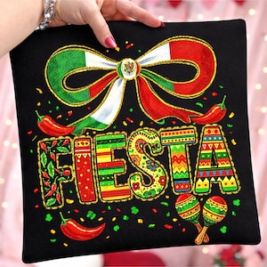 Puede incluir: Cojín negro con un diseño festivo. Presenta un gran lazo con los colores de la bandera mexicana, la palabra "FIESTA" en letras coloridas, chiles, confeti y maracas. Acentos de purpurina dorada adornan el diseño.