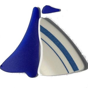 Può includere: Una collezione di tre pezzi di vetro marino e ceramica levigati e usurati. Un grande frammento di vetro marino blu cobalto vibrante, un frammento di ceramica bianca con due sottili strisce blu e un piccolo pezzo triangolare di vetro marino.