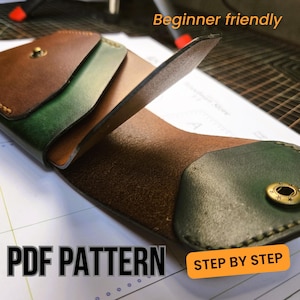 May include: A bi-fold leather wallet featuring a brown and green colour scheme with brass-toned snap buttons. The wallet is displayed on a white paper template with the text "Beginner friendly", "PDF PATTERN", and "STEP BY STEP".