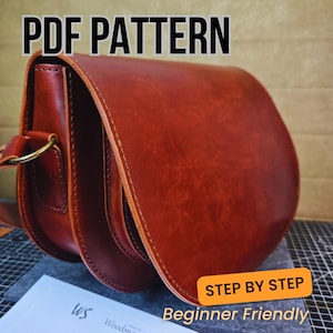 Peut inclure: Sacoche en cuir brun rougeâtre avec un rabat incurvé et une bandoulière. Le sac a un anneau en laiton circulaire sur le côté. Le texte "PDF PATTERN" est en haut et "STEP BY STEP Beginner Friendly" dans un encadré jaune.