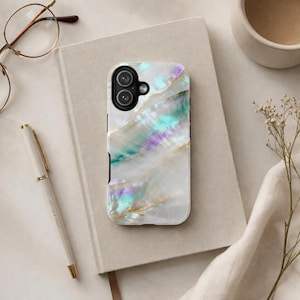 May include: A smartphone case with a pearlescent design. The case features a white base with iridescent teal, purple, and gold accents. The case has a black border and a camera cutout.