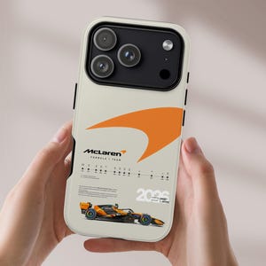 Puede incluir: Una funda de smartphone color crema con el logotipo de McLaren Formula 1 Team, un gráfico grande de color naranja y una ilustración detallada de un coche de carreras. El diseño incluye el texto 2026 y especificaciones técnicas en negro.