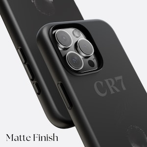 K&ouml;nnte beinhalten: Schwarze Handyh&uuml;lle mit mattem Finish, mit dem Text "CR7" und den Worten "Matte Finish". Die H&uuml;lle hat einen erh&ouml;hten Rand um die Kameralinsen und ein glattes, schlankes Design. Die H&uuml;lle ist f&uuml;r ein Smartphone konzipiert.