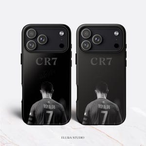 K&ouml;nnte beinhalten: Zwei schwarze Handyh&uuml;llen mit einem Schwarz-Wei&szlig;-Bild eines Fu&szlig;ballspielers. Auf den H&uuml;llen steht der Text "CR7" und "Ronaldo 7". Die H&uuml;llen sind f&uuml;r ein Smartphone.