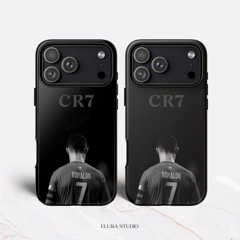 K&ouml;nnte beinhalten: Zwei schwarze Handyh&uuml;llen mit einem Schwarz-Wei&szlig;-Bild eines Fu&szlig;ballspielers. Auf den H&uuml;llen steht der Text "CR7" und "Ronaldo 7". Die H&uuml;llen sind f&uuml;r ein Smartphone.