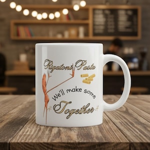 May include: White ceramic mug with the words "Rigatoni Pasta" and "We'll make some Together" in a decorative font. The mug features an illustration of pasta and a person. The mug has a large handle.
