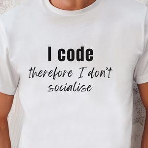 May include: White crew neck t-shirt featuring the black text "I code therefore I don't socialise". The shirt is worn with blue jeans and a black watch. The t-shirt's message is aimed at programmers and coders.