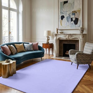 May include: A large, rectangular, solid lavender rug in a living room setting. The rug is the focal point, placed on a hardwood floor, with a teal sofa, patterned armchair, and abstract art in the background. The room has a classic, elegant style.