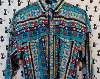 May include: A long-sleeved button-down shirt with a vibrant, patterned design. The shirt features a turquoise base color with stripes and geometric patterns in red, yellow, and white. It has two chest pockets and a classic collar, hanging on a wooden hanger.