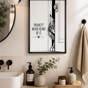 Könnte beinhalten: Ein schwarz-weiß gerahmter Wandkunstdruck, der eine Katze zeigt, die durch eine leicht geöffnete Tür späht. Der Text lautet, PRIVACY? NEVER HEARD OF IT. mit einem kleinen Pfotenabdruck-Symbol darunter. Die Illustration ist in klarem Linienstil.