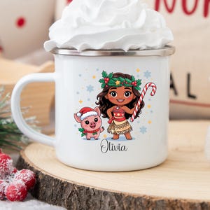 Puede incluir: Taza de esmalte blanco con una ilustraci&oacute;n de dibujos animados de una ni&ntilde;a y un cerdo con atuendos navide&ntilde;os. La taza tiene un borde plateado y un asa. El nombre "Olivia" est&aacute; impreso debajo de los personajes. Una pajita a rayas rojas y blancas est&aacute; en la crema batida.