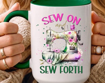 May include: White ceramic mug with a green handle and rim, featuring a colorful illustration of a sewing machine with floral accents. The mug has the text "SEW ON and SEW FORTH" in pink and green.