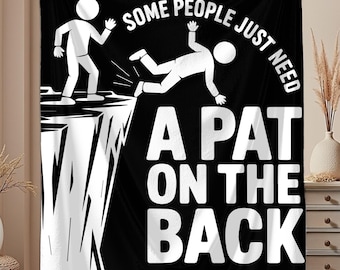 May include: Black blanket with a humorous graphic. The design features stick figures, one falling off a cliff, and the text "SOME PEOPLE JUST NEED A PAT ON THE BACK" in white. A fun, novelty item.