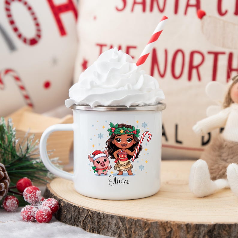Puede incluir: Taza de esmalte blanco con una ilustraci&oacute;n de dibujos animados de una ni&ntilde;a y un cerdo con atuendos navide&ntilde;os. La taza tiene un borde plateado y un asa. El nombre "Olivia" est&aacute; impreso debajo de los personajes. Una pajita a rayas rojas y blancas est&aacute; en la crema batida.