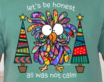May include: Light green t-shirt with a colorful cartoon bird and two Christmas trees. The text on the shirt reads "let's be honest all was not calm". The shirt is a solid color and has a crew neck.