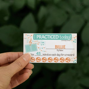 Könnte beinhalten: Eine weiße Karte mit einem türkisfarbenen Rand und Noten. Die Karte sagt "I PRACTICED today!" und hat einen Platz für einen Namen. Es steht "BILLIE" im Namensfeld. Die Karte sagt auch "45 minutes each day for a reward!" und hat eine Reihe von acht orangefarbenen Noten-Symbolen.