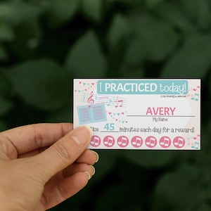 Könnte beinhalten: Ein rosa-blauer druckbarer Musik-Übungsplan mit dem Text "I practiced today!" und "Avery" mit einem Platz für einen Namen. Der Plan hat ein Musiknoten-Design und einen Platz, um 45 Minuten Übung pro Tag zu verfolgen.