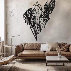 May include: A black metal wall art piece featuring a central figure with wings, positioned within a geometric diamond and triangle frame. The design depicts a stylized human form with draped fabric, flanked by a large bird with outstretched wings.